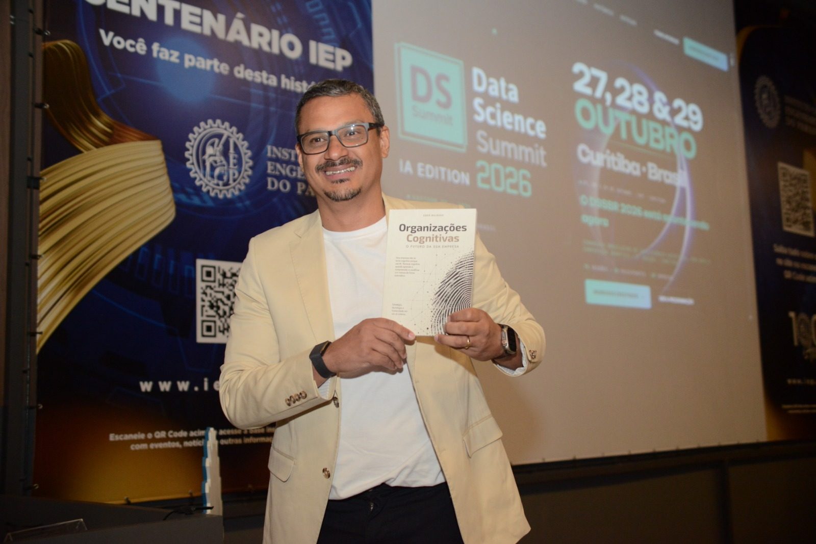 Eder Balbino segura o livro Organizações Cognitivas no palco do DSSBR 2026