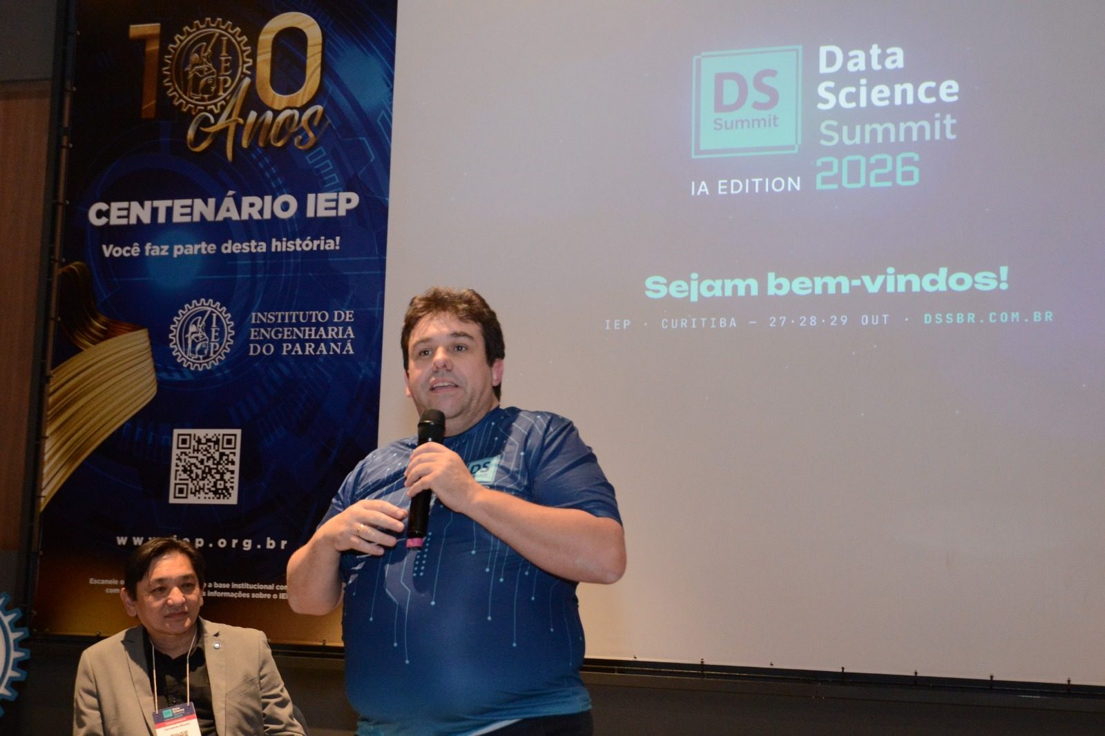 Alessandro Binhara fala na abertura do DSSBR 2026, diante do telão de boas-vindas